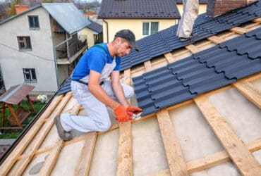 a professional master (roofer) with electric screwdriver covers repairs the roof